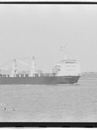 Schwarzweiß-Foto eines Frachtschiffs mit Aufbauten und zwei Ladekränen, das auf ruhigem Meer vor einer flachen Küstenlinie fährt; Wasserzeichen des Internationalen Maritimen Museums Hamburg unten links.