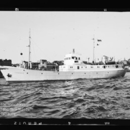 Schwarzweißaufnahme eines weißen Schiffes mit der Aufschrift 