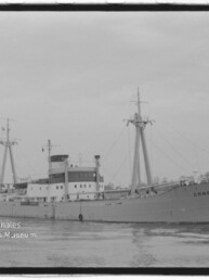 Schwarzweiß-Fotografie eines Frachtschiffs mit dem Namen CONGO am Bug, mittschiffs liegendem Aufbau, zwei Lade-Masten mit Tauwerken und ruhiger Wasseroberfläche, Museumswasserzeichen unten links.