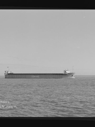 Schwarz-weiß-Foto eines langen Frachtschiffs mit der auf dem Rumpf lesbaren Aufschrift CON-RO, das ruhig auf dem Meer vor flachem Horizont fährt; linke untere Ecke zeigt das Wasserzeichen des Internationalen Maritimen Museums Hamburg.