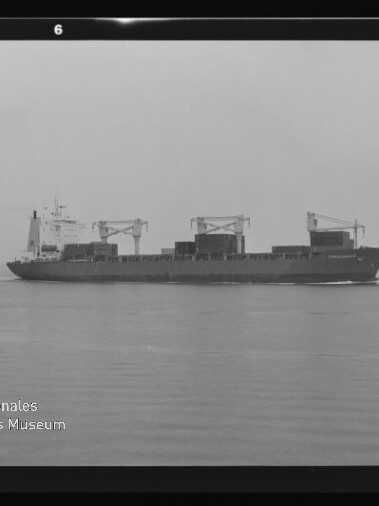 Schwarzweiß-Fotografie eines Containerschiffs in Seitenansicht auf ruhiger See, mit drei Ladekränen und Containerstapeln auf dem Deck und dem Logo des Internationalen Maritimen Museums Hamburg unten links.