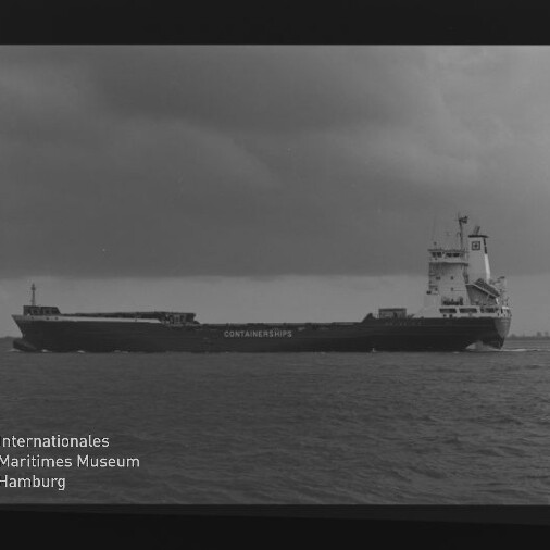 Schwarzweiß-Aufnahme eines Containerschiffs in Seitenansicht auf ruhiger See unter bewölktem Himmel, mit rückwärtigem Aufbauturm, dem Schriftzug CONTAINERSHIPS am Rumpf sowie sichtbarem Filmrand und Wasserzeichen des Internationalen Maritimen Museums Hamburg