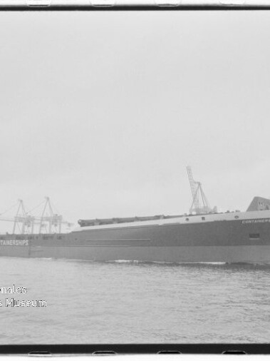 Schwarzweißfoto eines großen Containerschiffs mit dem Schriftzug ‚CONTAINERSHIPS‘, das vor einem Industriehafen mit Ladekränen auf ruhiger See vorbeifährt.