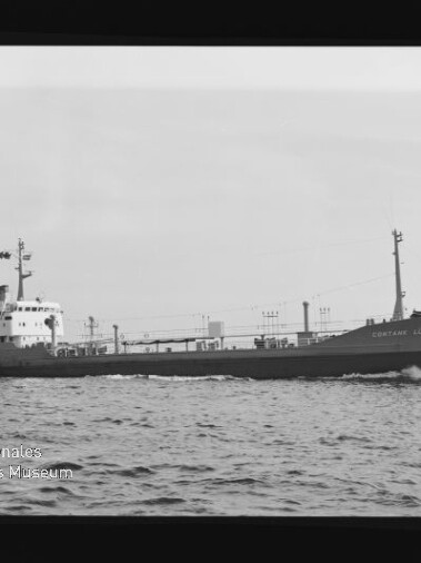 Schwarzweiß-Seitenaufnahme des Frachtschiffs Captain Lübeck, das mit sichtbarem Schiffsname über ruhige See fährt; links unten das Logo und Wasserzeichen des Internationalen Maritimen Museums Hamburg.