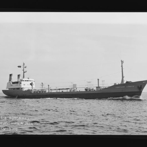 Schwarzweiß-Seitenaufnahme des Frachtschiffs Captain Lübeck, das mit sichtbarem Schiffsname über ruhige See fährt; links unten das Logo und Wasserzeichen des Internationalen Maritimen Museums Hamburg.