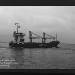 Schwarz-weiß-Foto eines Frachtschiffs mit dem Namen CONTIMAR und zwei Ladekränen, das bei bedecktem Himmel über ruhiger See fährt; links sind Filmränder und unten das Logo „Internationales Maritimes Museum Hamburg“ sichtbar.