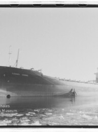 Schwarzweißfoto eines großen Frachtschiffs namens Conti Jork, seitlich im Hafen auf teilweise zugefrorenem Wasser mit Eisschollen liegend, mit markantem Bug und Aufbauten achtern; Wasserzeichen des Internationalen Maritimen Museums Hamburg unten links.