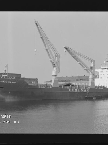 Schwarzweißaufnahme eines am Industriehafen vertäuten Frachtschiffs mit der Beschriftung CONTIMAR, zwei ausgefahrenen Deckskränen, Lagerhallen im Hintergrund, Wasser im Vordergrund sowie sichtbaren Filmrand- und Wasserzeichenmarken.