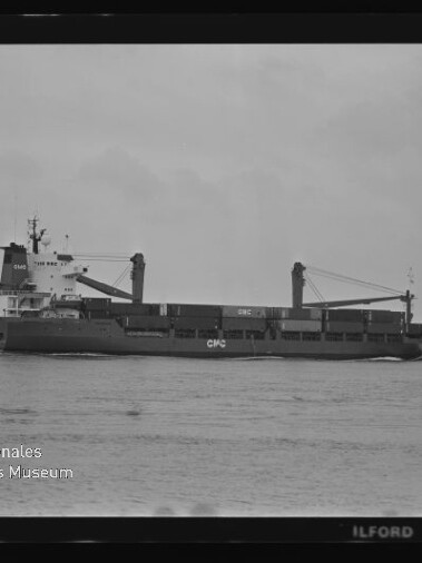 Schwarzweiß-Fotografie eines Frachtschiffs in Seitenansicht auf ruhiger See mit zwei Ladekränen und der Aufschrift „CPC“, sichtbar sind Filmrand und Wasserzeichen des Internationalen Maritimen Museums Hamburg.