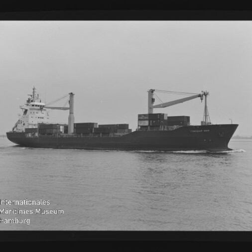 Schwarzweißaufnahme eines Containerfrachters mit gestapelten Containern und zwei Auslegerkränen, der über ruhiges Wasser fährt; unten links ist das Logo des Internationalen Maritimen Museums Hamburg zu sehen.