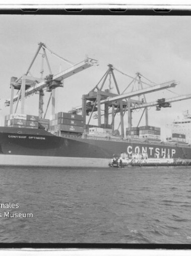 Großes Containerschiff CONTSHIP OPTIMISM am Hafen neben mehreren Auslegerkränen, mit Containern an Deck und Wasser im Vordergrund, Museumswasserzeichen unten links