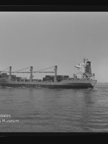 Schwarzweiß-Seitenansicht eines mit Containern beladenen Containerschiffs mit zwei Ladekränen auf ruhiger See, im Vordergrund Wasser und unten links das Logo des Internationalen Maritimen Museums Hamburg.