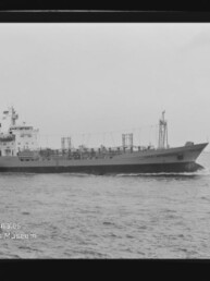 Schwarzweiß-Seitenaufnahme eines Frachttankers, der mit leichter Bugwelle auf offenem Meer fährt, sichtbar sind das Heckaufbauhaus, Masten und Tankdeckausrüstung; unten links das Wasserzeichen des Internationalen Maritimen Museums Hamburg.