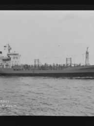 Schwarzweiß-Seitenansicht eines Frachtschiffs auf ruhiger See mit sichtbaren Aufbauten, Ladegestängen und Filmrand; Wasserzeichen des Internationalen Maritimen Museums Hamburg unten links.