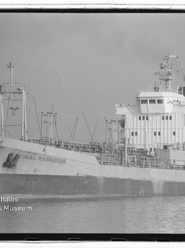 Schwarzweiß-Seitenansicht des Frachtschiffs Coral Essberger auf ruhigem Wasser mit komplexen Decksaufbauten und Rohrleitungen; links unten Logo und Schriftzug 'Internationales Maritimes Museum Hamburg'.