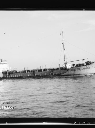 Schwarzweiß-Foto eines Frachtschiffs mit dem Namen Cabo Eckelmann, seitliche Ansicht bei ruhiger See mit Aufbauten achtern, Mast über dem Laderaum und Museumswasserzeichen unten links.