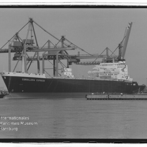 Großes Frachtschiff „Cordillera Express“ liegt am Kai eines Containerterminals vor mehreren hohen Verladekränen, mit ruhiger Wasserfläche im Vordergrund und einem Museumslogo unten links.