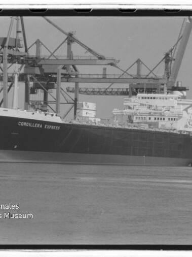 Großes Frachtschiff namens Cordillera Express am Kai eines Containerhafens vor mehreren hohen Hafenkränen, mit Wasser im Vordergrund und einem Wasserzeichen des Internationalen Maritimen Museums Hamburg in der linken unteren Ecke.