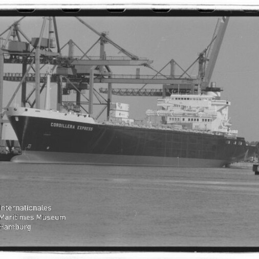 Großes Frachtschiff namens Cordillera Express am Kai eines Containerhafens vor mehreren hohen Hafenkränen, mit Wasser im Vordergrund und einem Wasserzeichen des Internationalen Maritimen Museums Hamburg in der linken unteren Ecke.
