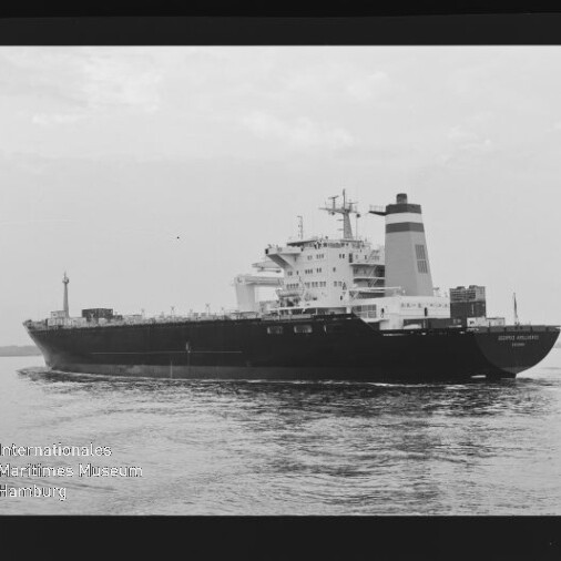Schwarzweiß-Fotografie eines großen Frachtschiffs mit markantem Schornstein und Aufbauten am Heck, das ruhig auf dem Meer fährt; schwarzer Filmrand und Wasserzeichen des Internationalen Maritimen Museums Hamburg sind sichtbar.
