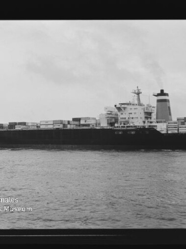 Schwarzweiß-Seitenansicht eines beladenen Containerschiffs auf ruhiger See mit gestapelten Containern, markanten Aufbauten und Schornstein, aufgenommen innerhalb eines sichtbaren Filmrahmens mit Filmmarkierungen und dem Logo des Internationalen Maritimen Museums Hamburg.