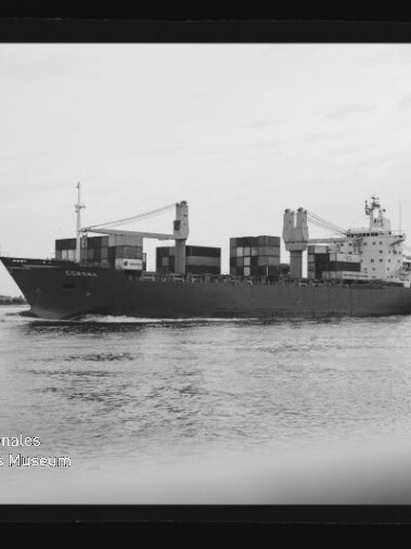 Schwarzweiß-Foto eines Containerschiffs, das mit gestapelten Containerblöcken und zwei Ladekränen über ruhigem Wasser fährt, mit Wasserreflexionen im Vordergrund und einem Wasserzeichen des Internationalen Maritimen Museums Hamburg links unten.