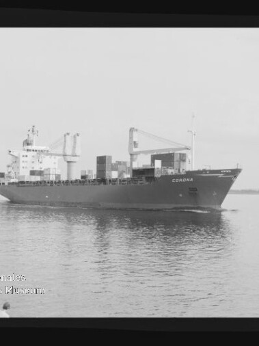 Schwarzweiß-Aufnahme eines beladenen Containerschiffs namens „CORONA“ auf ruhigem Wasser mit Ladekränen und mehreren Containerstapeln, daneben ein kleines Begleitboot und sichtbarer Filmrand samt Museums-Wasserzeichen.