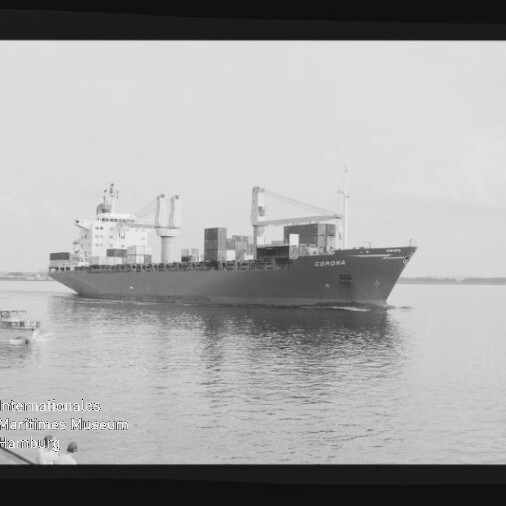 Schwarzweiß-Aufnahme eines beladenen Containerschiffs namens „CORONA“ auf ruhigem Wasser mit Ladekränen und mehreren Containerstapeln, daneben ein kleines Begleitboot und sichtbarer Filmrand samt Museums-Wasserzeichen.