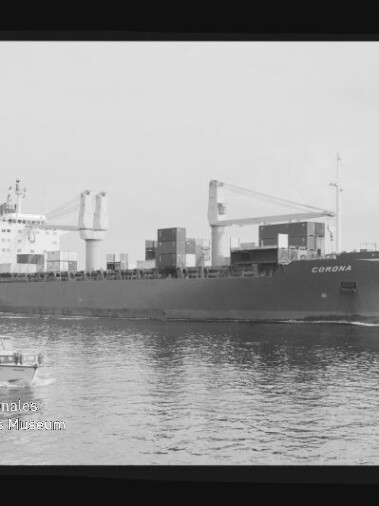 Schwarz-weiß-Foto eines Containerschiffs mit dem Schriftzug CORONA, beladen mit Containern und sichtbaren Ladekränen, das auf ruhigem Wasser vorbeifährt; im Vordergrund ein kleines Motorboot sowie Filmrand und Museumswasserzeichen am Bildrand sichtbar.