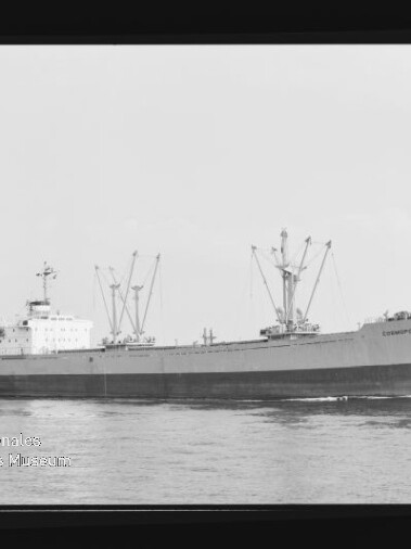 Schwarzweißaufnahme eines Frachtschiffs mit mehreren Ladekränen, das auf ruhiger See fährt; links unten ist das Wasserzeichen des Internationalen Maritimen Museums Hamburg sichtbar.