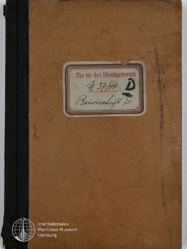 Braunes, abgenutztes Notizbuch mit schwarzem Leinenrücken und in der Bildmitte einem abgerundeten Etikett mit rotem Rahmen, dem Aufdruck „Nur für den Dienstgebrauch“ sowie handschriftlichen Nummern und Markierungen; unten links das Logo des Internationalen Maritimen Museums Hamburg.