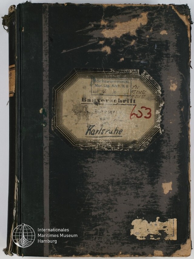 Abgenutztes dunkelgrünes bis schwarzes Buch mit stark abgegriffenem Einband und beschädigten Kanten; mittig ein achteckiges, vergilbtes Etikett mit verblasstem Druck, handschriftlicher Ortsangabe 
