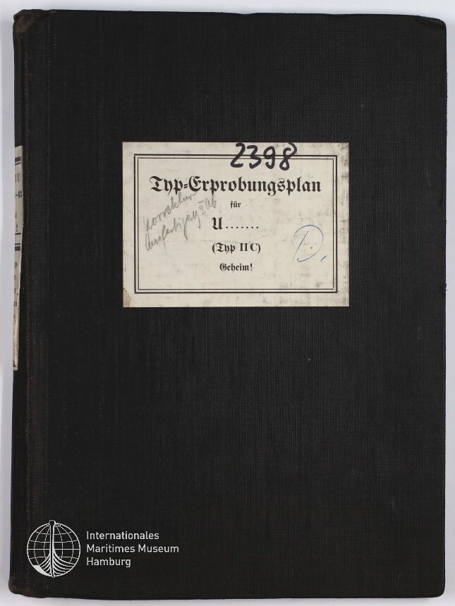Schwarzer Leineneinband eines Ordners mit rechteckigem, leicht verschmutztem weißen Etikett in der Mitte, darauf in gebrochener Schrift 