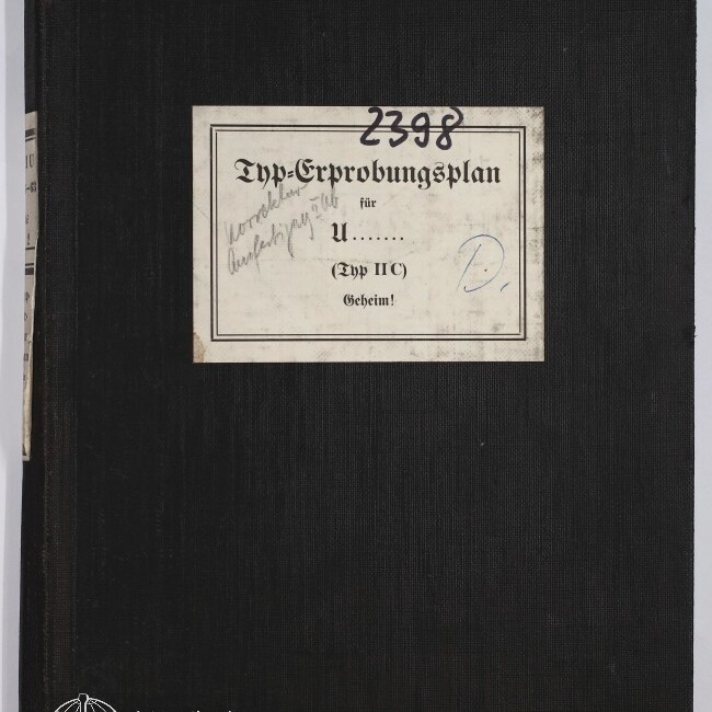 Schwarzer Leineneinband eines Ordners mit rechteckigem, leicht verschmutztem weißen Etikett in der Mitte, darauf in gebrochener Schrift 