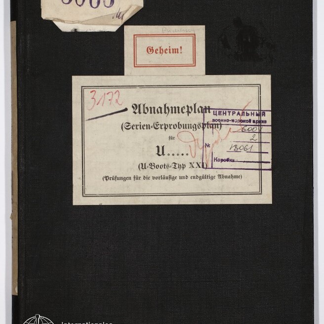 Schwarzer Archivordner mit mehreren aufgeklebenen Etiketten — oben links die eingestempelte Zahl 5066, mittig ein roter Kasten mit der Aufschrift ‚Geheim!‘ und darunter ein größeres Etikett ‚Abnahmeplan (Serien-Erprobungsplan) für U…‘ mit Stempeln und handschriftlichen Vermerken; unten links das Logo und der Schriftzug Internationales Maritimes Museum Hamburg.