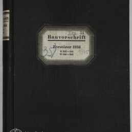 Schwarzer Leinen-Buchband mit mittig aufgeklebtetem, achteckigem Etikett mit der Aufschrift 'Bauvorschrift Zerstörer 1934' und handschriftlichen Nummern; unten links kleines Logo und Schriftzug des Internationalen Maritimen Museums Hamburg.