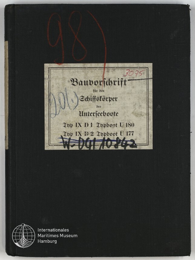 Schwarzer Leineneinband eines Buches mit einer vergilbten, mittigen Etikette in Frakturschrift Bauvorschrift für den Schiffskörper der Unterseeboote, roten und blauen Handschrift- und Stempelmarkierungen sowie dem Logo des Internationalen Maritimen Museums Hamburg unten links.