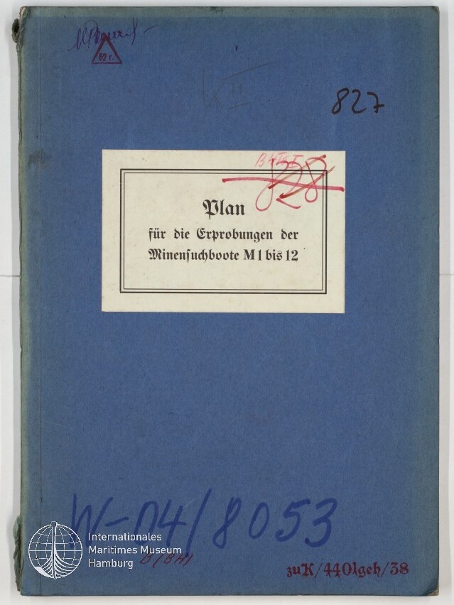 Blaue Deckmappe mit einem weißen Etikett, auf dem in Frakturschrift steht „Plan für die Erprobungen der Minensuchboote M 1 bis 12“, mit handschriftlichen Notizen, roten Streichungen und dem Logo des Internationalen Maritimen Museums Hamburg in der Ecke.