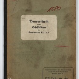 Verschmutzter grüner Einband eines alten technischen Hefts mit mittig aufgeklebtem weißen Etikett mit dem Titel Bauvorschrift für den Schiffskörper der Torpedoboote T5, 7 u. 8, roten Stempeln und Museumswasserzeichen unten links