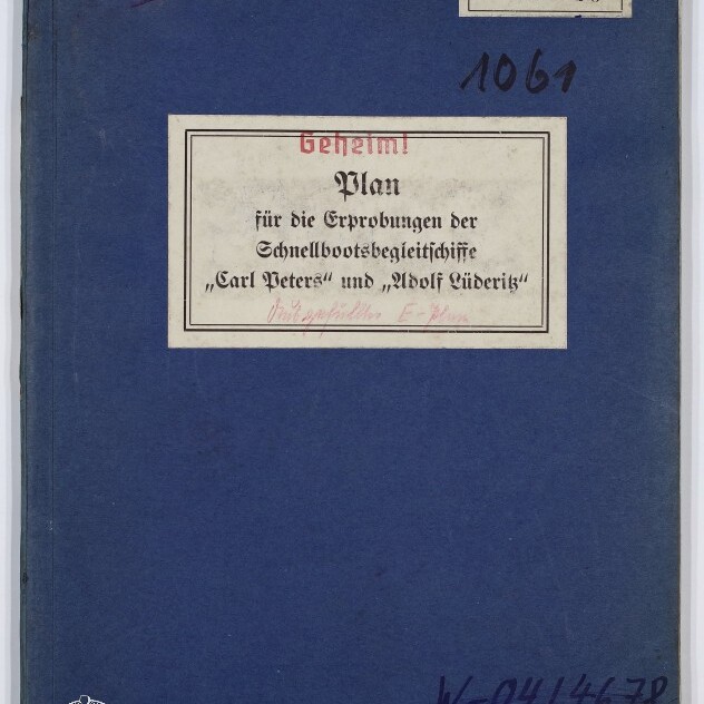 Blauer Einband eines historischen Hefts mit mittiger Etikette 'Geheim! Plan für die Erprobungen der Schnellbootsbegleitschiffe „Carl Peters“ und „Adolf Lüderitz“', handschriftlichen Nummern, Stempeln und einem Museumslogo in der unteren Ecke.