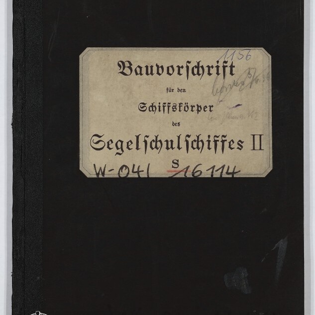 Schwarzer Buchumschlag mit einem beigefarbenen Etikett in Frakturschrift mit der Aufschrift „Bauvorschrift für den Schiffskörper des Segelschulschiffes II“, handschriftlichen Nummern und dem Logo des Internationalen Maritimen Museums Hamburg unten links.