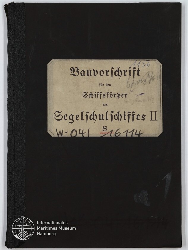 Schwarzer Buchumschlag mit einem beigefarbenen Etikett in Frakturschrift mit der Aufschrift „Bauvorschrift für den Schiffskörper des Segelschulschiffes II“, handschriftlichen Nummern und dem Logo des Internationalen Maritimen Museums Hamburg unten links.