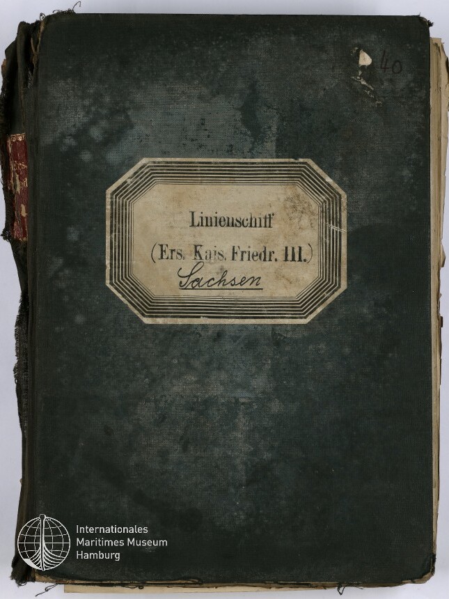 Abgenutztes dunkelgrünes Buchcover mit eingerissenem Rücken und mittig aufgeklebetem, rahmenverziertem Etikett mit der Aufschrift Linienschiff (Ers. Kais. Friedr. III.) Sachsen, handschriftlicher Nummer 40 oben rechts und Museumslogo unten links.
