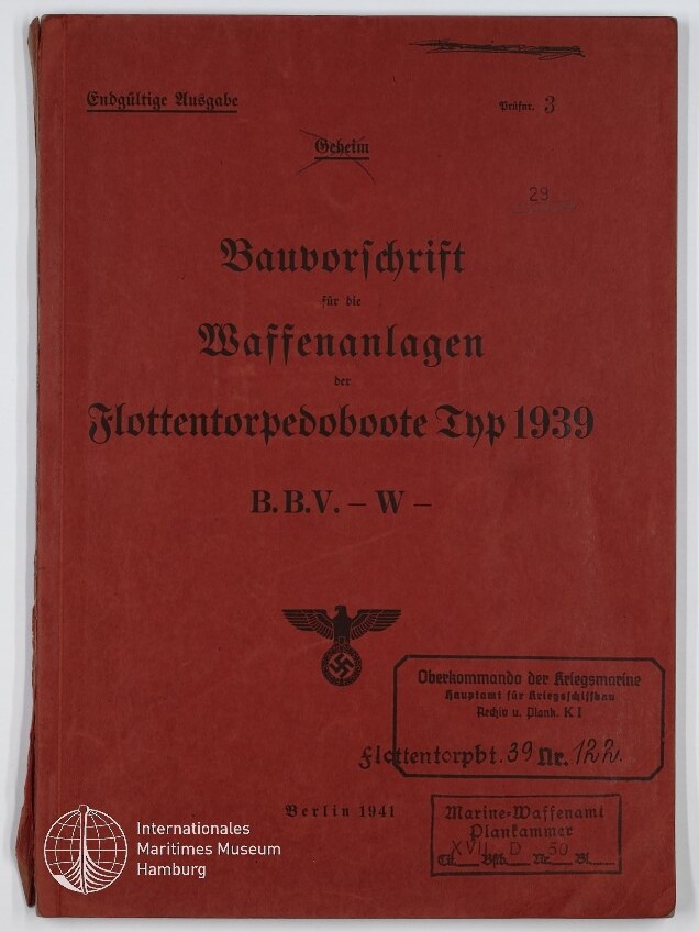 Rotes Deckblatt eines 1941 in Berlin erschienenen deutschen Marinehandbuchs mit schwarzer Frakturschrift »Bauvorschrift für die Waffenanlagen der Flottentorpedoboote Typ 1939«, Stempeln und handschriftlichen Markierungen sowie einem Hoheitszeichen Adler mit Hakenkreuz und einem Museumssignet unten links.