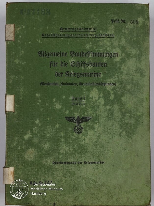 Grünes, stark vergilbtes und fleckiges Buchcover mit dem gedruckten Titel Allgemeine Baubestimmungen für die Schiffsbauten der Kriegsmarine, einem Reichsadler mit Hakenkreuz in der Mitte, handschriftlichen/stempelartigen Nummern oben links und dem Museumslogo Internationales Maritimes Museum Hamburg unten links