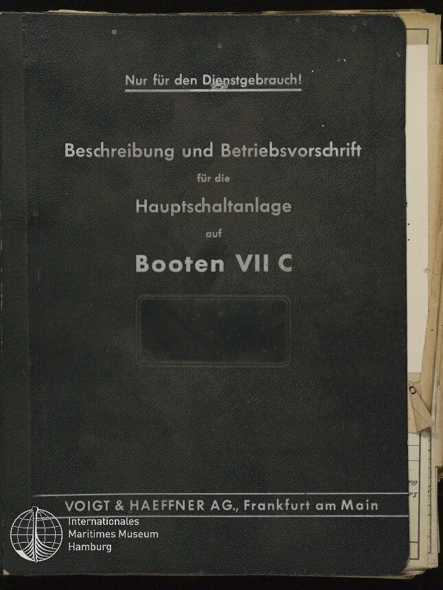 Schwarzer Ordnerumschlag mit weißer Aufschrift 'Nur für den Dienstgebrauch! Beschreibung und Betriebsvorschrift für die Hauptschaltanlage auf Booten VII C', Verlagszeile 'Voigt & Haeffner AG, Frankfurt am Main' und Museumssiegel unten links, an der rechten Seite herausragende Papiere.