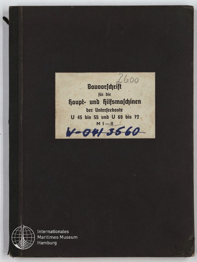 Schwarzer Hardcover-Ordner mit mittig aufgeklebtem rechteckigem Etikett in Frakturschrift mit dem Titel einer Bauvorschrift für U-Boote und handschriftlichen Nummern in Bleistift (2600) und blauer Tinte, unten links das Signet des Internationalen Maritimen Museums Hamburg.