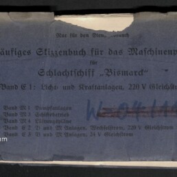 Abgewetztes blaues Heft mit deutschem Titel „Vorläufiges Skizzenbuch für das Maschinenpersonal für Schlachtschiff ‚Bismarck‘ — Band C1: Licht- und Kraftanlagen, 220 V Gleichstrom“, handschriftlichen Markierungen, kleinem weißen Aufkleber oben links, roter Zahl oben rechts und dem Logo des Internationalen Maritimen Museums Hamburg unten links.