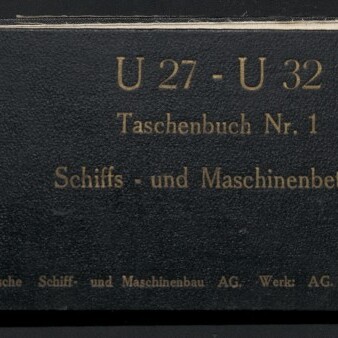 Schwarzer, länglicher Lederumschlag eines Taschenbuchs mit goldgeprägter Schrift 'U 27 - U 32 Taschenbuch Nr. 1 Schiffs- und Maschinenbetrieb', links oben kleine Papieretikette mit der Zahl 36 und links unten Logo und Schriftzug des Internationalen Maritimen Museums Hamburg.