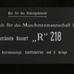 Schwarzer Einband eines Dienstgebrauchs-Skizzenbuchs mit weißer Typografie 'Nur für den Dienstgebrauch' und dem Titel 'Skizzenbuch für die Maschinenmannschaft für Räumboote Bauart „R“ 218', links zwei Metallnieten und ein Museumslogo, rechts eine Farbreferenzkarte.